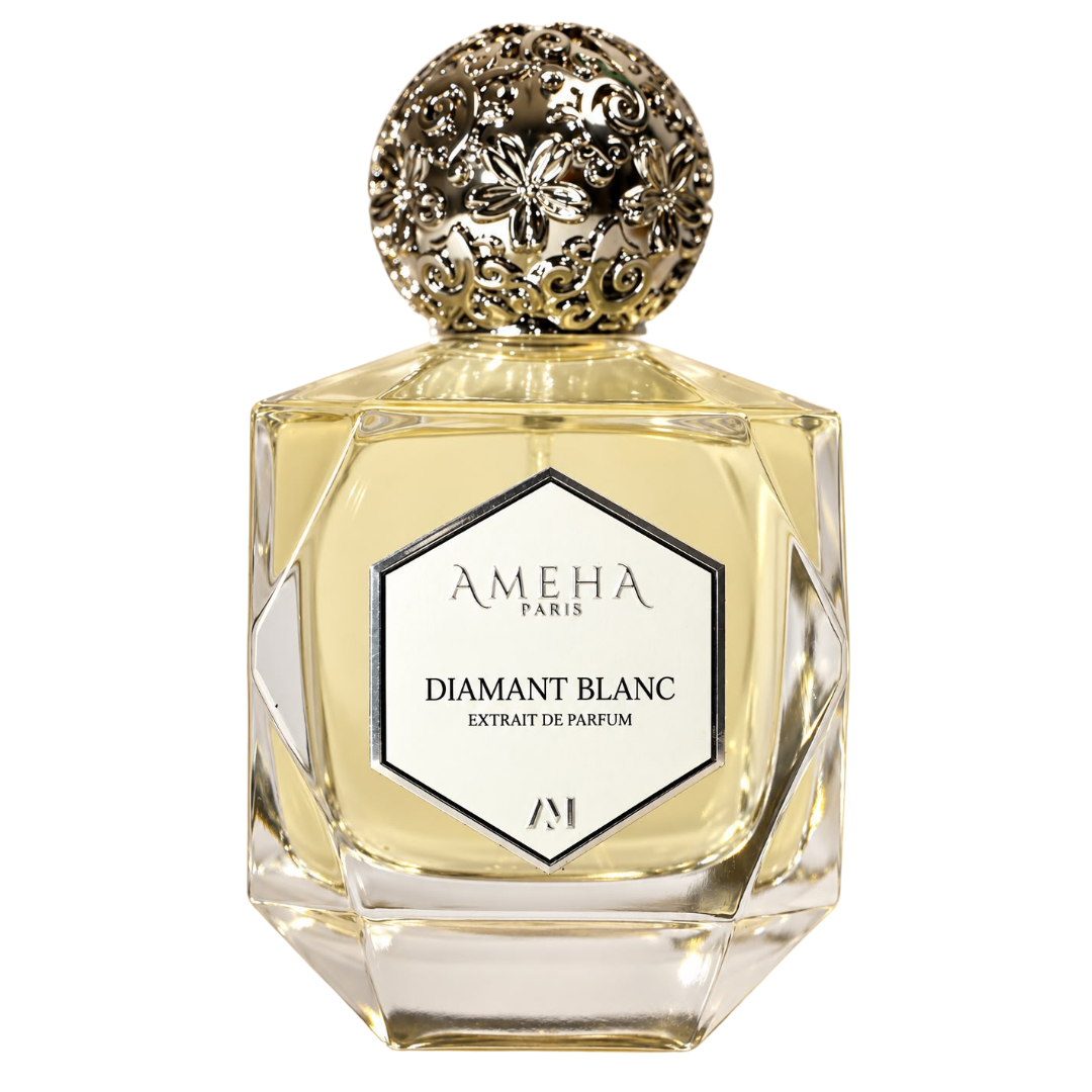 A faceted glass perfume bottle filled with pale golden liquid, featuring a round ornate gold cap and a white front label that reads AMEHA PARIS DIAMANT BLANC EXTRAIT DE PARFUM.