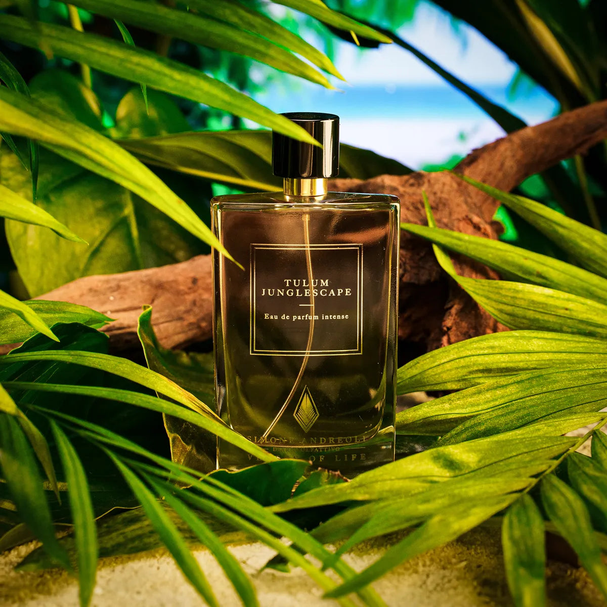 A bottle of Simone Andreoli Tulum Extrait de Parfum 3.4 oz Unisex placed among green leaves and wooden elements, suggesting a tropical theme.