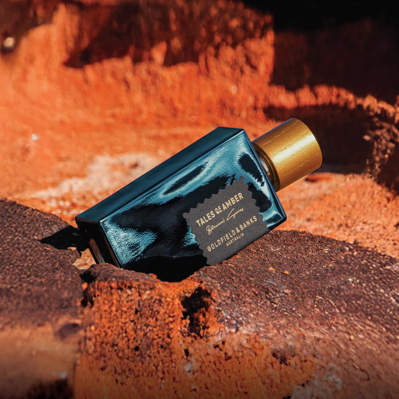 Blue and gold perfume bottle on a textured orange-brown surface