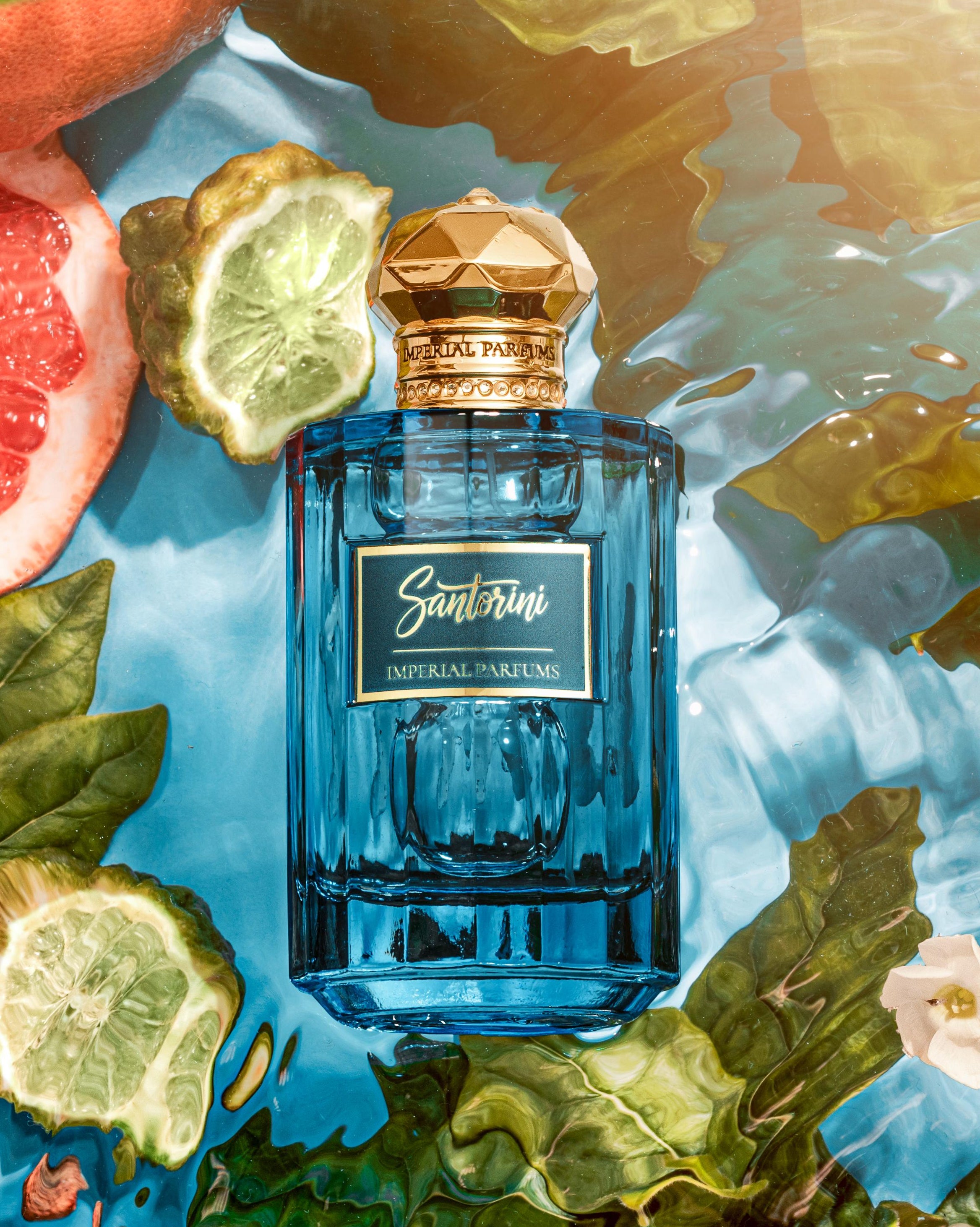 Blue perfume bottle with gold cap on a colorful fruit and leaf background