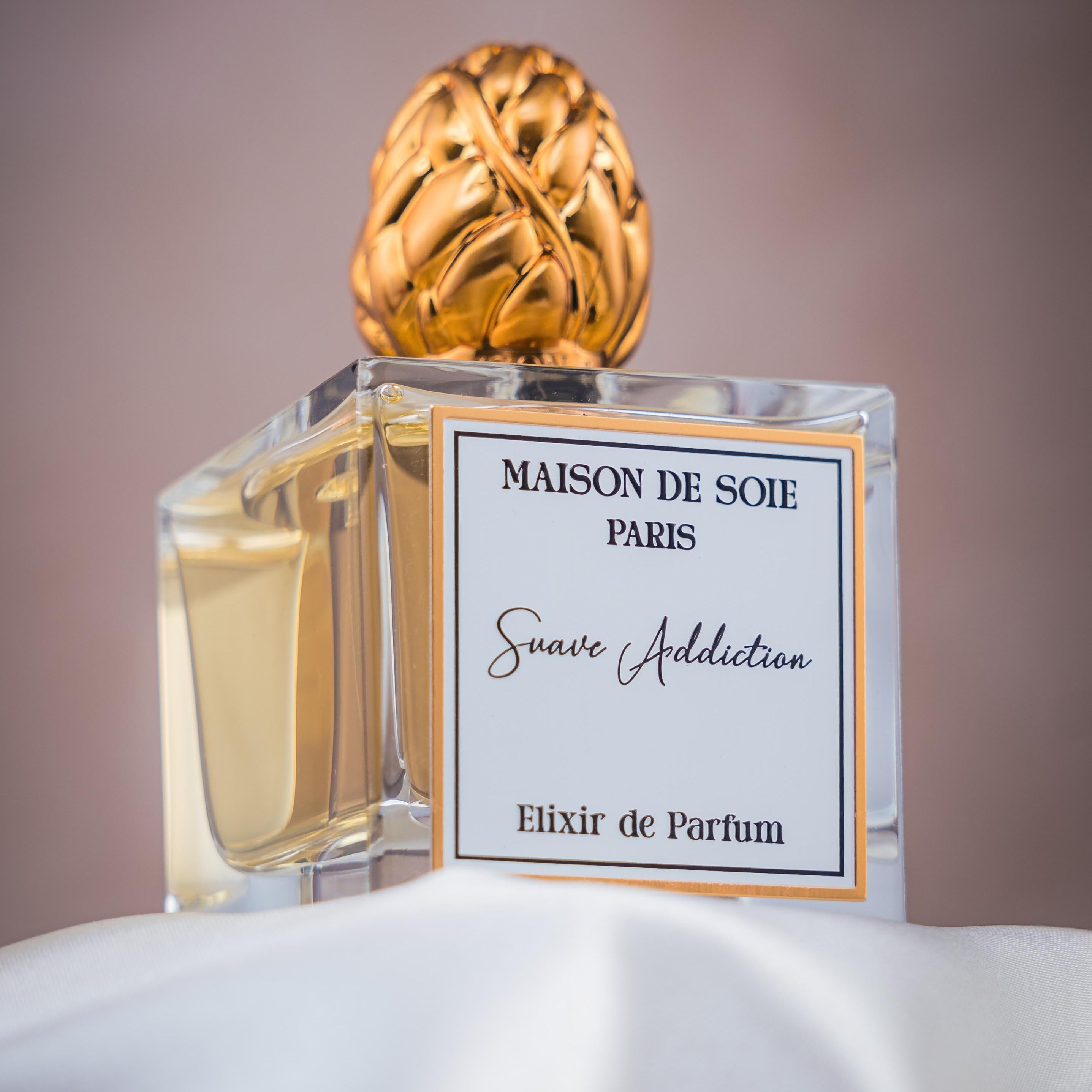 Perfume bottle with gold cap and clear label on a white surface with gradient background