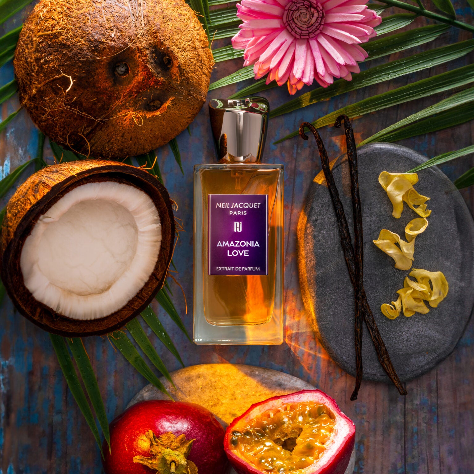 Perfume bottle labeled 'Amazonia Love' surrounded by tropical fruits and flowers on a textured surface.