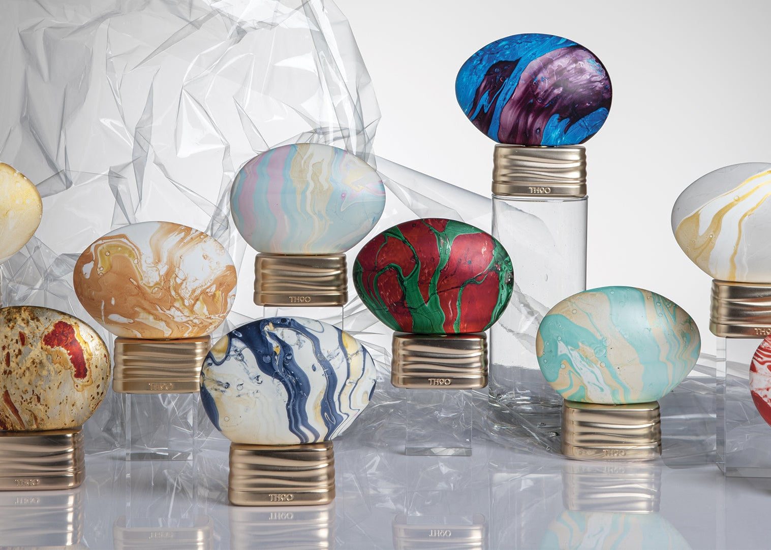 Colorful marbled egg-shaped objects on a reflective surface with a white background