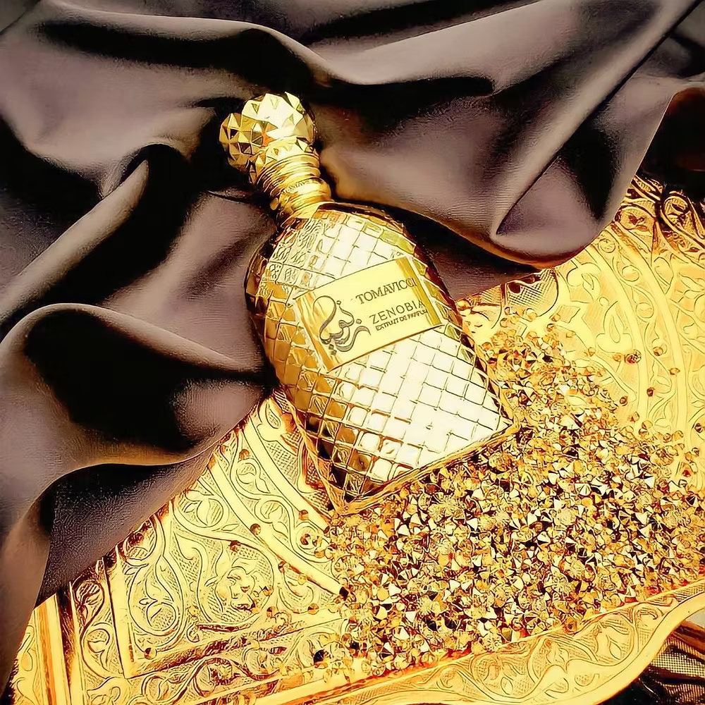 Gold perfume bottle with intricate design on a luxurious gold and black fabric background