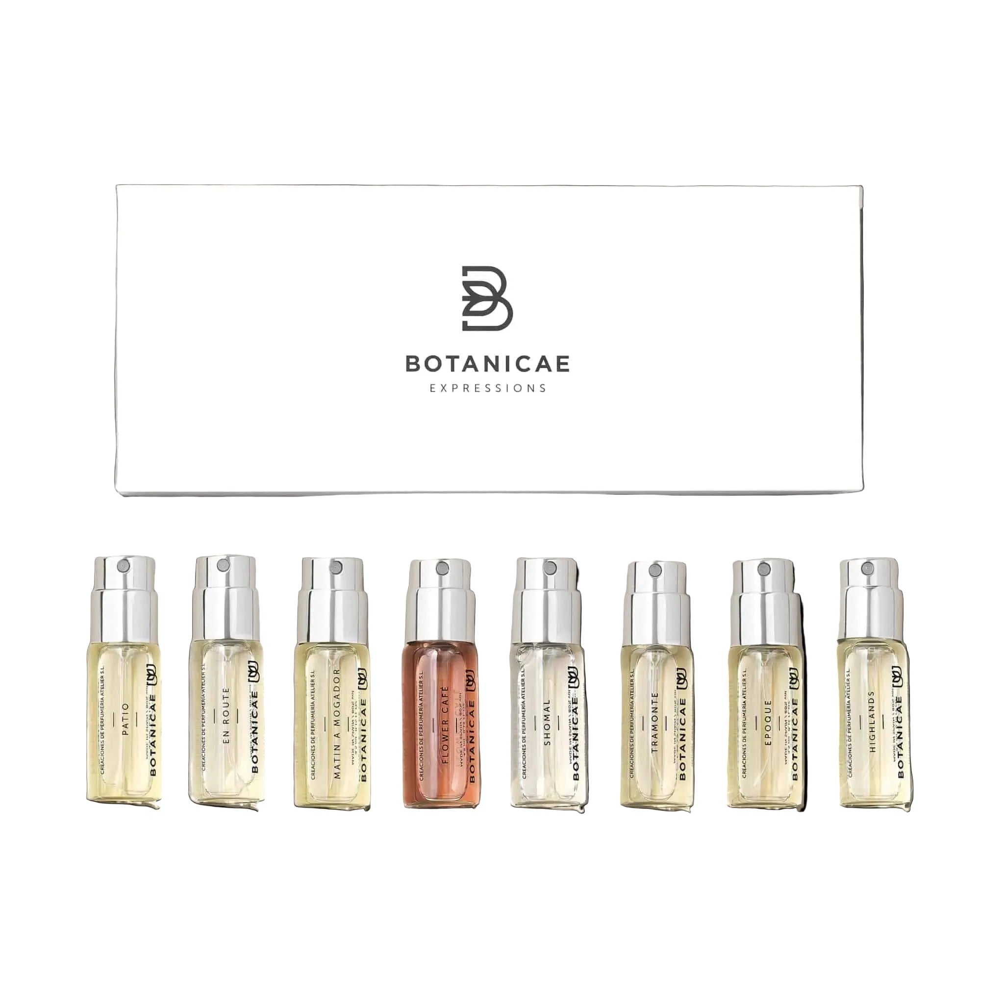 A set of ten small, clear glass vials with white caps, labeled with different scent names, arranged in front of a white box with the Botanicae brand logo.