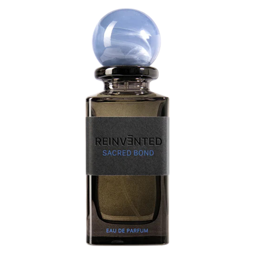 A bottle of Reinvented Sacred Bond Eau de Parfum with a clear liquid visible through the transparent glass. The bottle has a modern design with a blue cap and label.