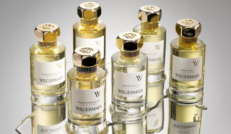 Set of Wilgermain perfume bottles with gold caps on a reflective surface.